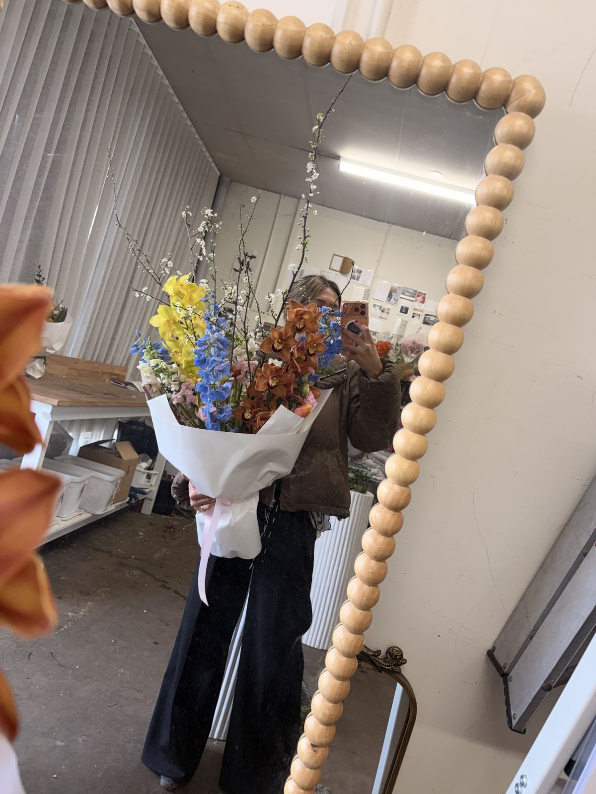Youki of Sugar Bee Flowers holding the finished 10-year anniversary bouquet in the studio mirror