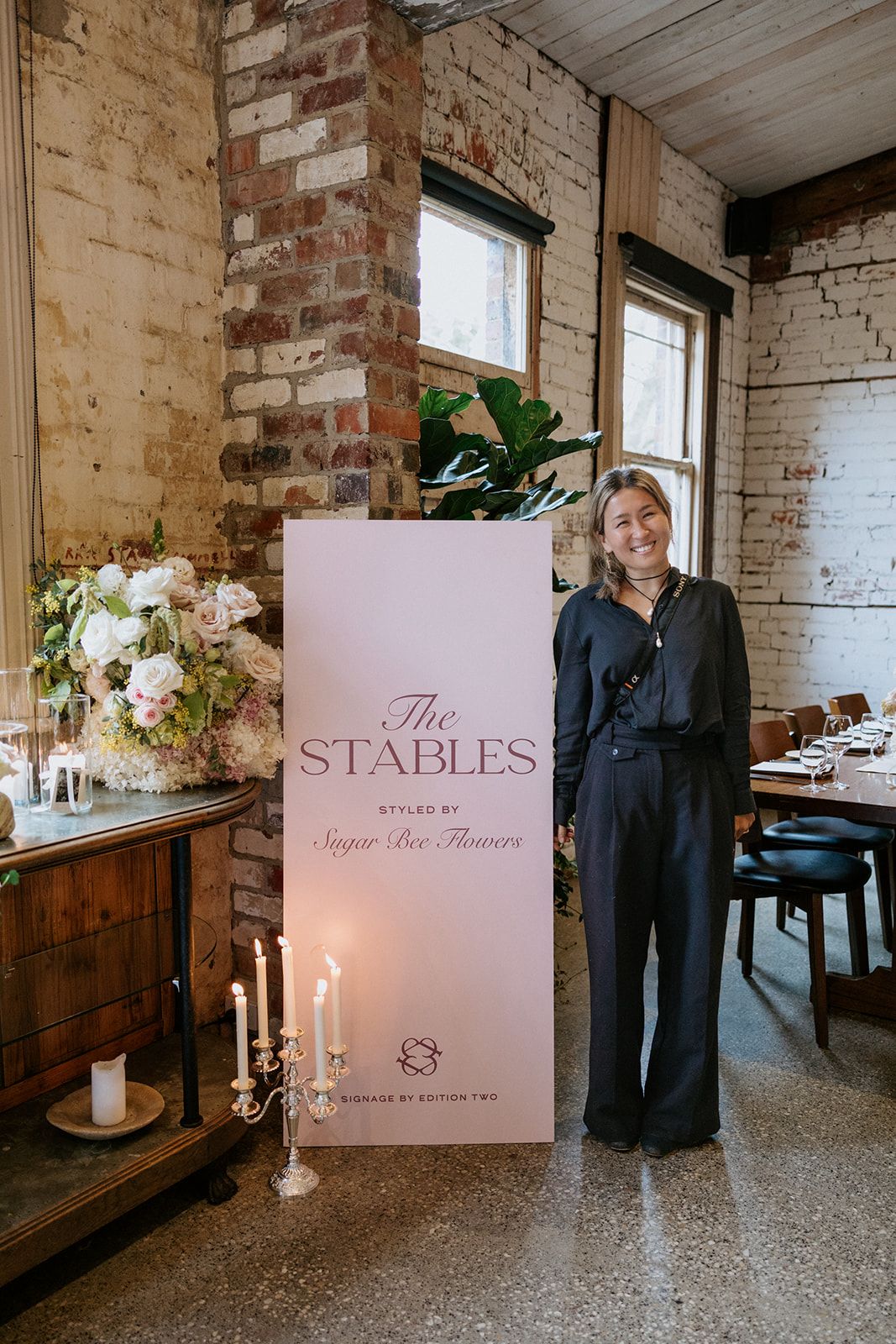 Youki beside The Stables signage, styled by Sugar Bee Flowers, at the Stones Unveiling