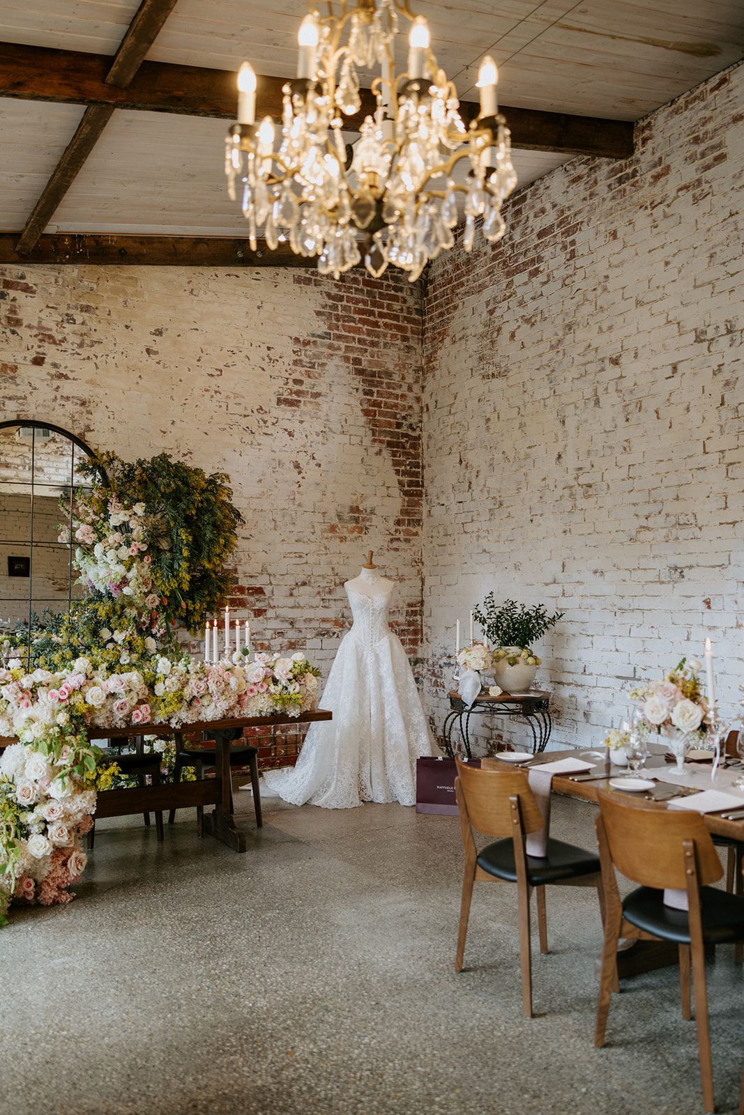 Blossom and mimosa installation beside a gown on display under the chandelier at The Stables Restaurant